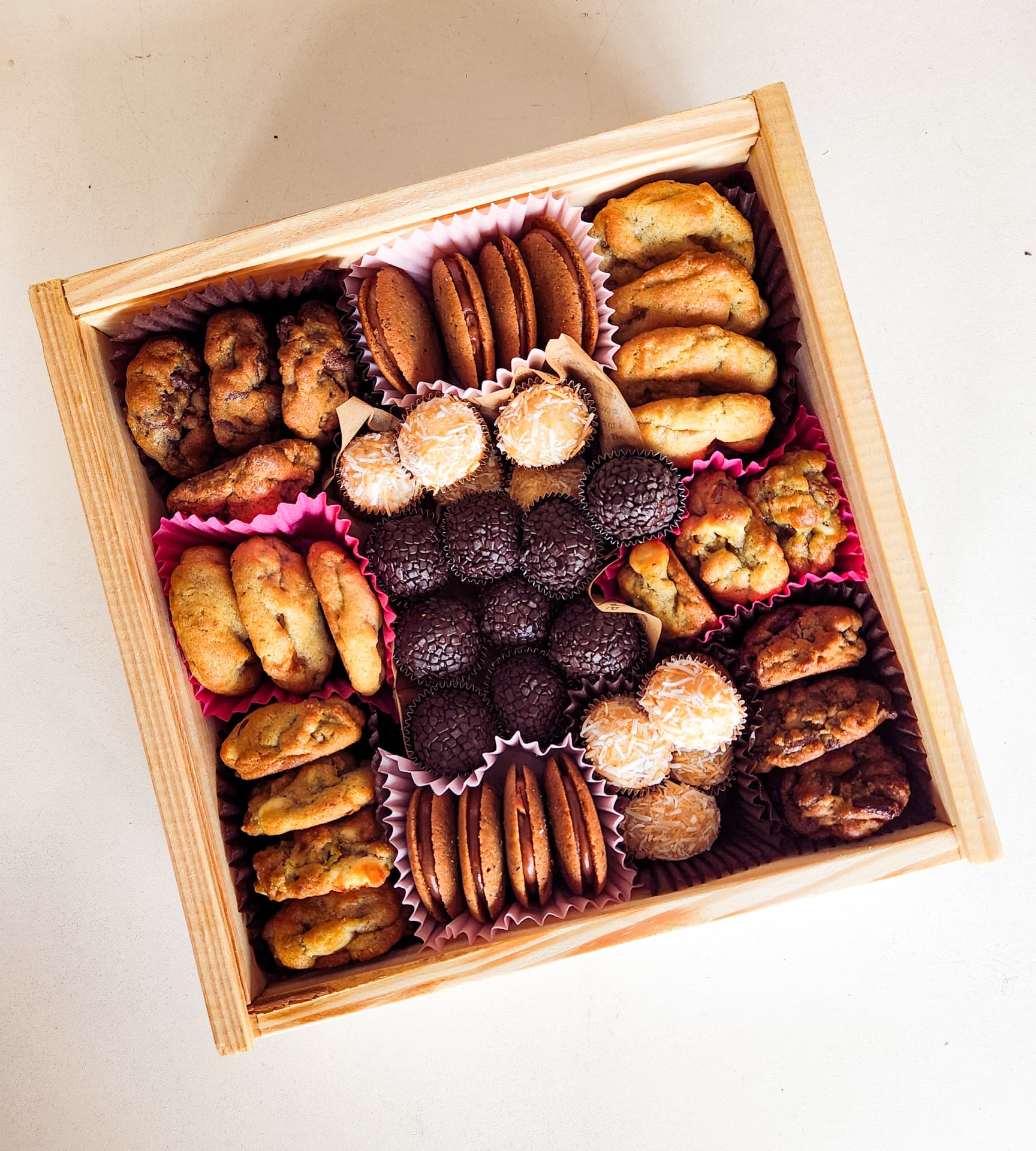 Caixa Deli Delicadezas aberta, com biscoitos e docinhos organizados no interior